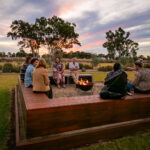 A group of people laughing around a firepit