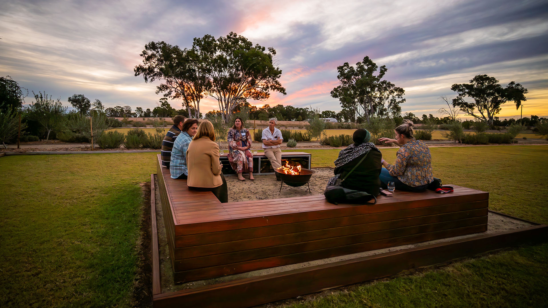 A group of people laughing around a firepit