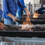 A man forging a tool in burning coals