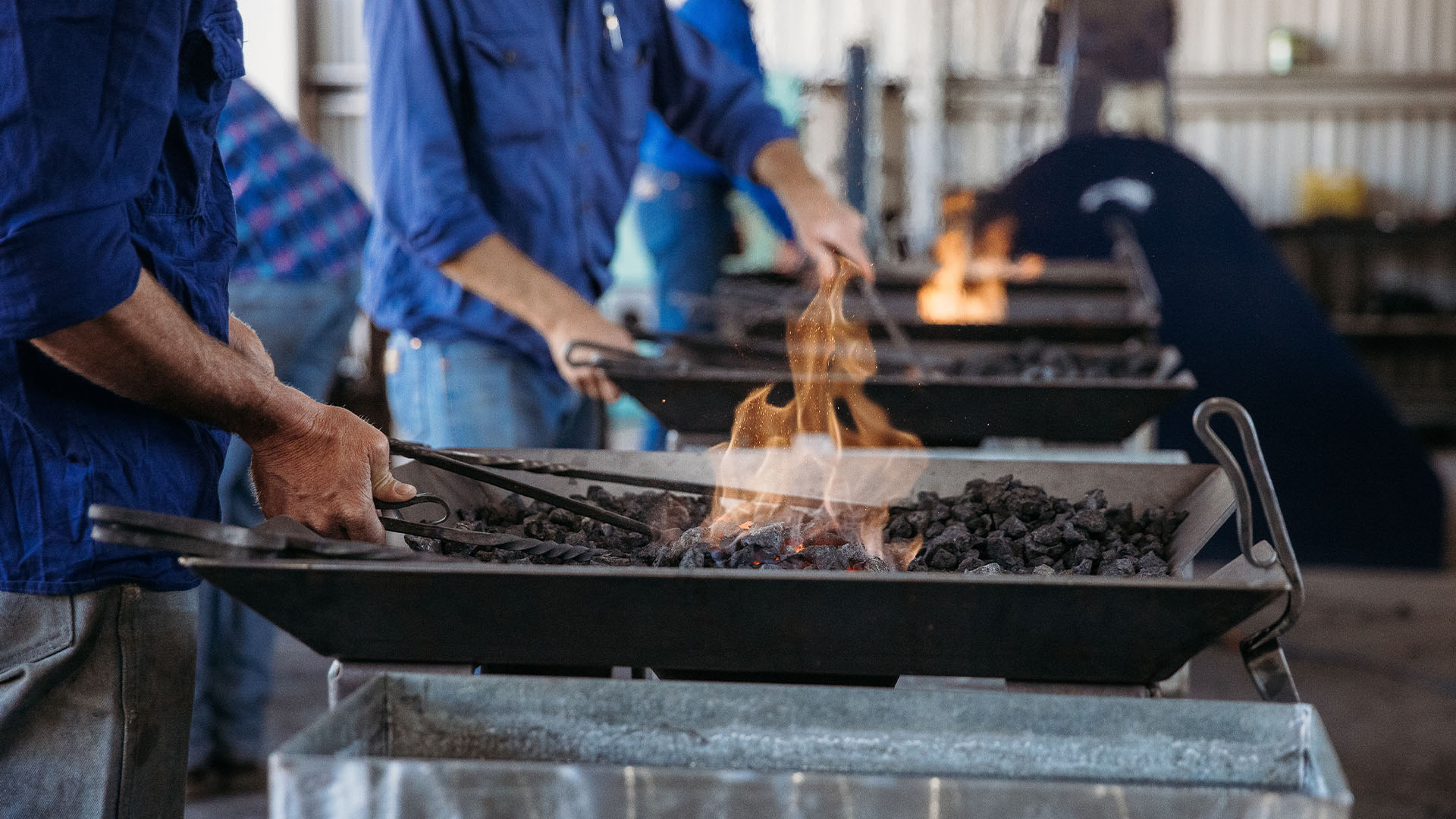 A man forging a tool in burning coals